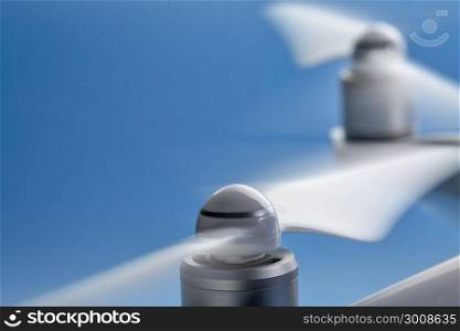 blurred spinning propellers of a drone against blue sky with a copy space