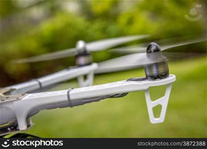 blurred spinning propellers of a hexacopter drone flying over green area