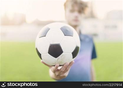 blurred sportsman showing soccer ball
