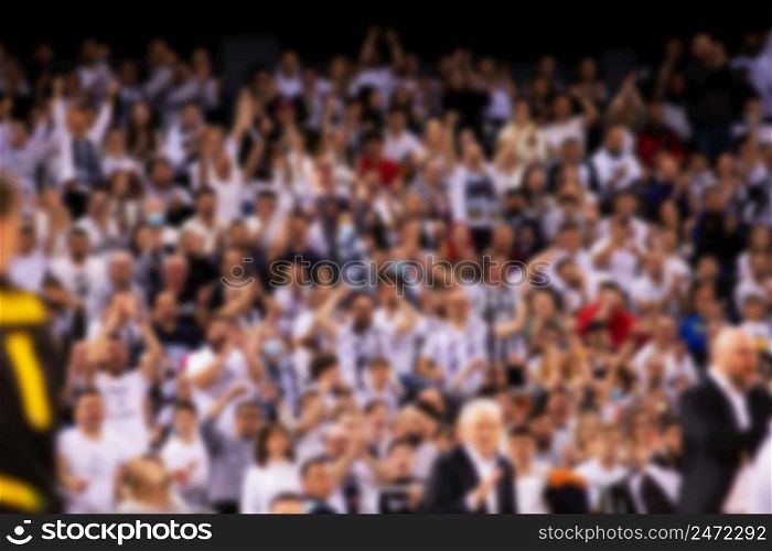 blurred supporters crowd in a basketball court during game