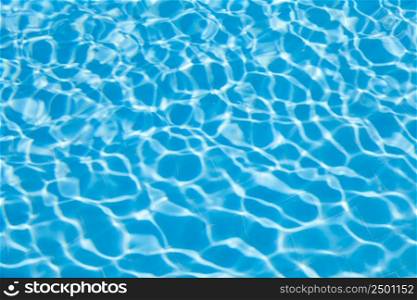Blurred transparent ripple of blue clear water texture in a swimming pool in sunlight. Abtract view of water wave in sunlight using as background.