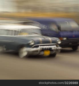 Blurred view of a car and a van on a road, Havana, Cuba