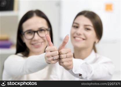 blurred young businesswomen showing thumb up sign toward camera