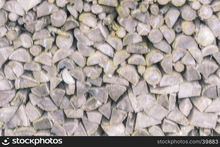 Blurry background with a pile of chopped firewood logs in different shapes