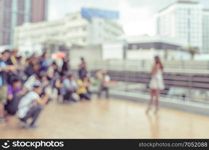 Blurry image of Photographers shooting a woman on city street in vintage filter effect