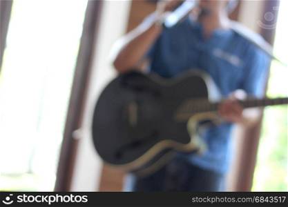 blurry photo of musician playing guitar with hand holding microphone. blurry photo of musician playing guitar