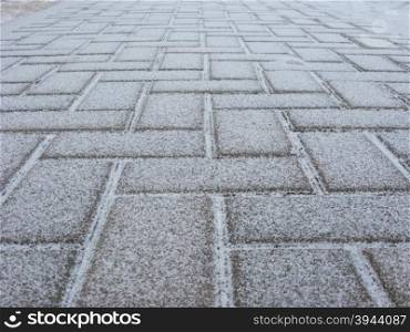 Blurry texture of paving slabs covered with a thin layer of snow