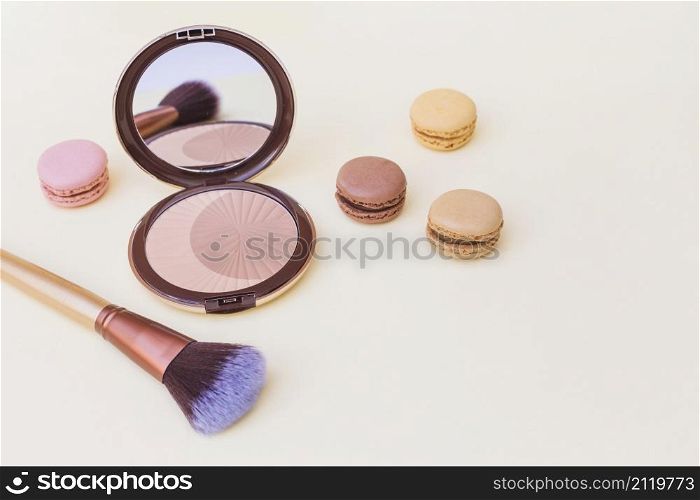 blusher with macaroon makeup brush beige background
