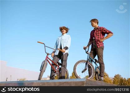 Bmx bikers, teenagers poses on r&in skatepark. Extreme bicycle sport, dangerous cycle exercise, street riding, biking in summer park. Bmx bikers, teenagers poses on r&in skatepark