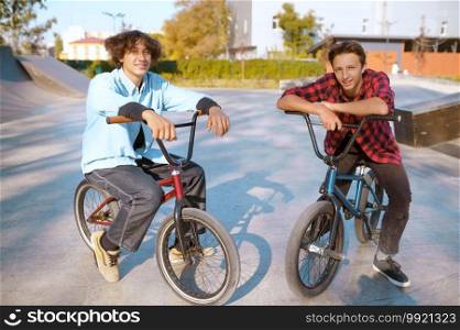 Bmx riders on bikes, training on r&in skatepark. Extreme bicycle sport, dangerous cycle exercise, street riding, teens biking in summer park. Bmx riders on bikes, training on r&in skatepark