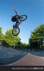 Bmx stunt performed at the top of a mini ramp on a skatepark.