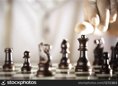 Board game, chess player hand about to play, excellence concept.. Chess player