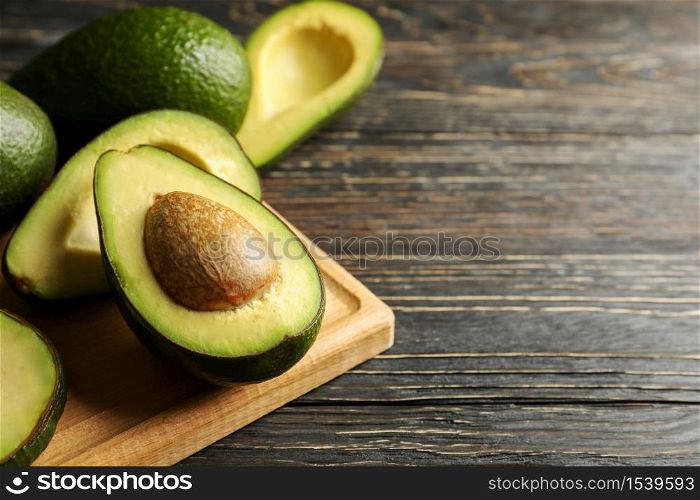 Board with avocado on wooden background, close up