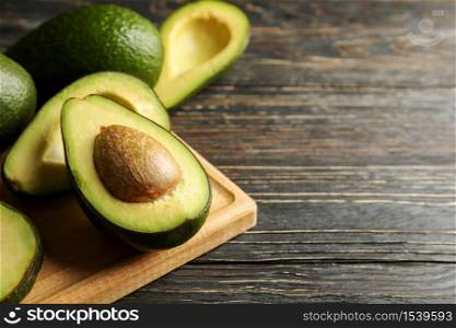 Board with avocado on wooden background, close up