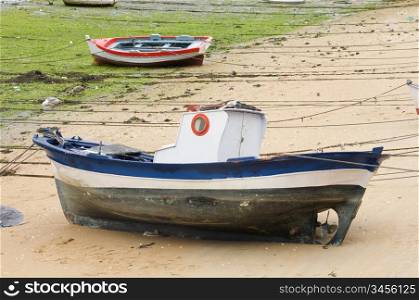 Boat and little fishing ship on the sand with low tide