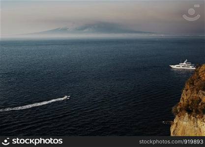 Boat at sea leaving a wake. boat in the sea, mountain on the background of the sea. Sorrento, view over Neapolitan Bay. boat in the sea, mountain on the background of the sea. Sorrento, view over Neapolitan Bay