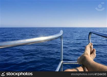 Boat bow summer vacation with male man feet relaxed over blue ocean sea