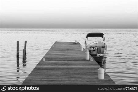 Boat docked at the jetty at sunrise in stunning black and white