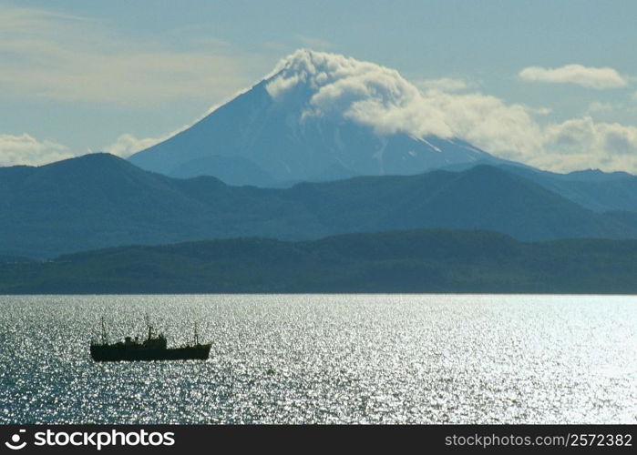 Boat in the river with a volcano in the background, Viluchinsky Volcano, Bay of Petropavlovsk, Kamchatka, Russia