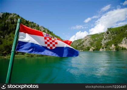 Boat on a river to Waterfalls of Krka National Park. Croatian Flag
