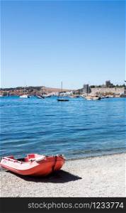 Boat on stony beach with castle in the background, Bodrum, Turkey