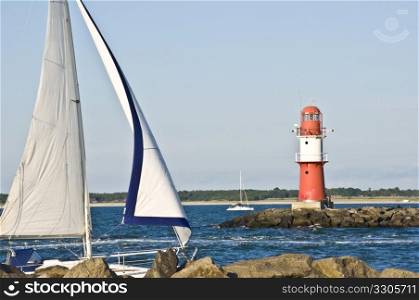 boat passing a red lighthouse on its way into the harbor