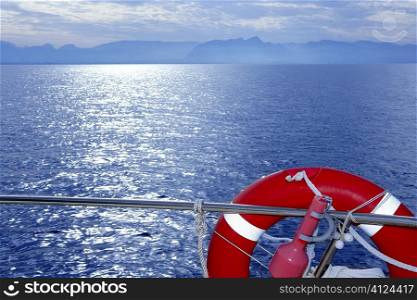 Boat rail with round orange lifesaver and blue sunset sea ocean