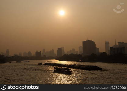 Boat traffic on the river, Bangkok City, behind a tall building in the city during the morning.