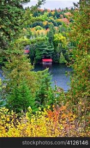 Boathouse on lake through fall forest with colorful trees