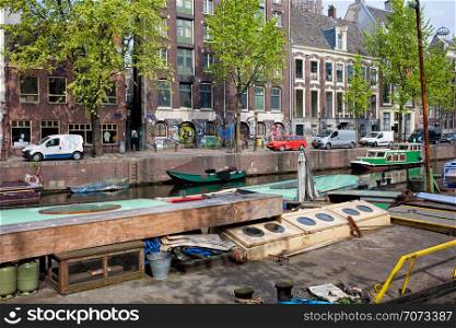 Boats and row houses on Geldersekade canal in the city of Amsterdam, Netherlands, North Holland province.