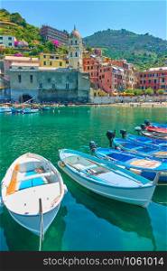 Boats at harbour and waterfront with buildings by the sea in Vernazza town on sunny summer day, Cinque Terre, Italy