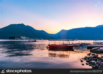 Boats in Adriatic sea with the view on Mountains and beautiful sunset in Perast, Montenegro. Boats in Perast at sunset
