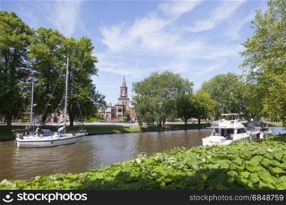 boats in canal near centre of old dutch town leeuwarden, capital of friesland, with church in the background