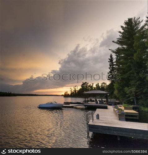 Boats moored at a dock in the lake, Lake of The Woods, Ontario, Canada