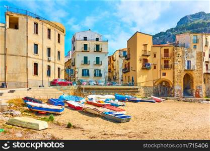 Boats on sandy beach and old colorful houses by the sea in the old town of Cefalu in Sicily, Italy