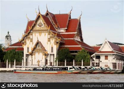 Boats on the Chao Phraya river near buddhist temple, Bangkok, Thailand