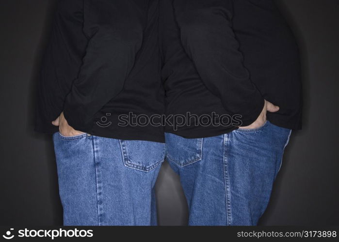 Bodies of Caucasian mid adult identical twin men standing back to back.