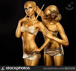 Body Art. Woman painting Body with Paint Brush in Golden Color. Gold Make Up