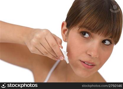 Body care - Female teenager cleaning face with cotton pad, removing make-up