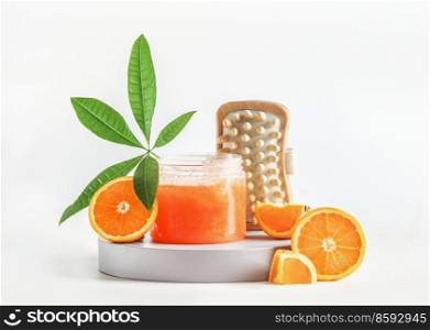 Body care setting with orange sugar scrub, sliced oranges, green leaf and massage brushes at white background. Healthy skin care products for body treatment. Front view.