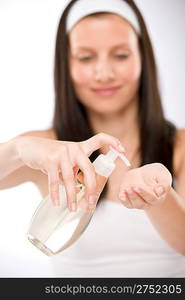 Body care - woman applying massage oil on white background, focus on bottle