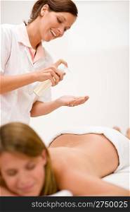 Body care - woman back massage, masseus holding bottle with oil