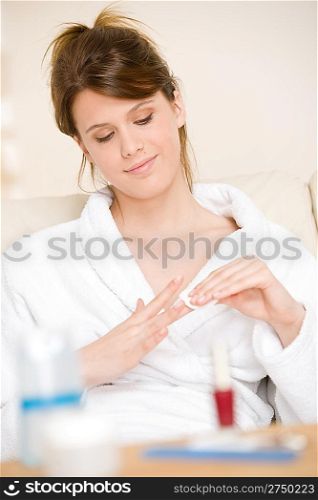 Body care - woman remove nail polish home with cotton pad in lounge wearing bathrobe