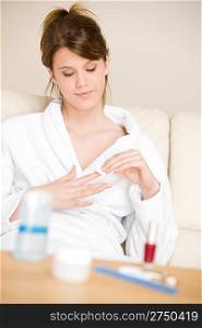 Body care - woman remove nail polish home with cotton pad in lounge wearing bathrobe