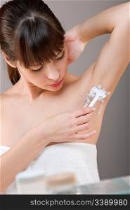Body care: Woman shaving armpit with razor in bathroom
