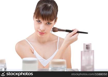 Body care: Young woman applying powder with make-up brush on white background