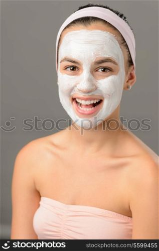 Body care young woman white facial mask smiling on gray background