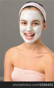 Body care young woman white facial mask smiling on gray background