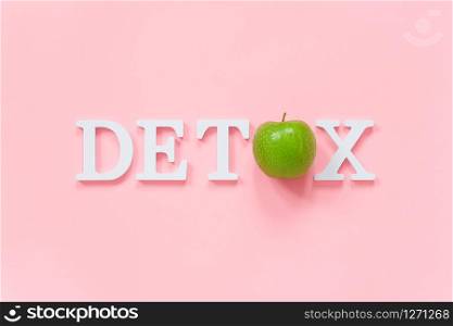 Body detoxification and healthy diet concept. Green natural fresh apple in word DETOX from white letters on pink background. Creative flat lay Top view Copy space.. Body detoxification and healthy diet concept. Green natural fresh apple in word DETOX from white letters on pink background. Creative flat lay Top view Copy space