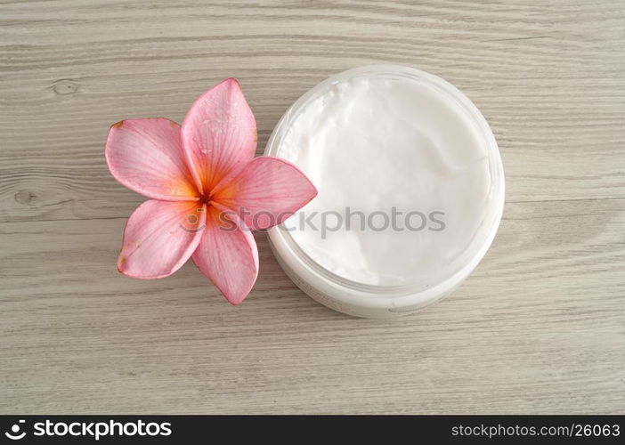 Body lotion in a container with a pink frangipani flower